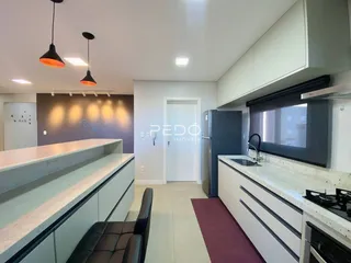 Vista da cozinha moderna com armários brancos e bancadas claras.