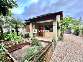 Fachada de uma residência em Lajeado, Brasil, com jardim frontal e calçada de tijolos.
