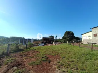 Paisagem de um terreno com vegetação e estruturas ao fundo.
