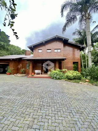Fachada de uma casa de tijolos vermelhos com jardim em Lajeado, Brasil.