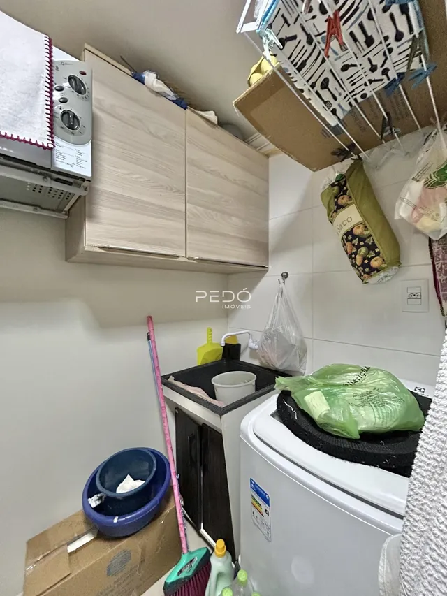 Interior de uma área de serviço com armários e máquina de lavar roupa.
