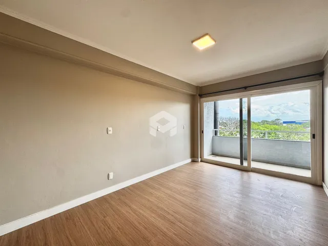 Vista interna de uma sala com piso de madeira clara e porta de vidro.