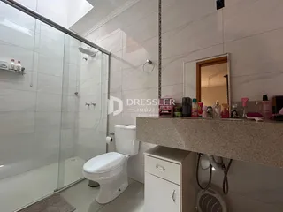 Foto de um banheiro com box de vidro e vaso sanitário.