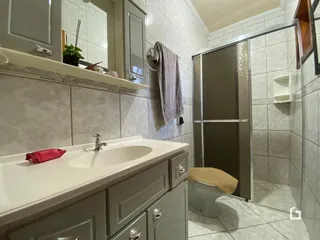 Foto de um banheiro com revestimento de cerâmica e box de vidro.