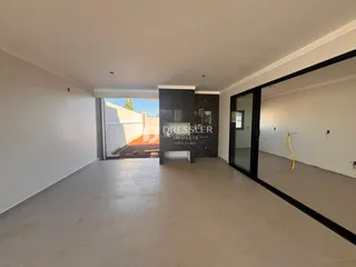 Interior de um espaço com piso claro e parede de mármore escuro.
