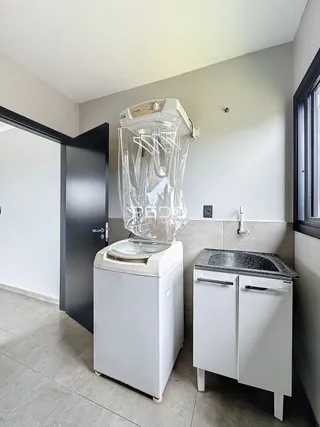 Foto de uma área de serviço com um tanque e um aparelho grande em um imóvel.