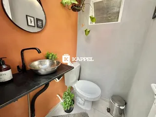 Banheiro com pia de metal e vaso sanitário branco.