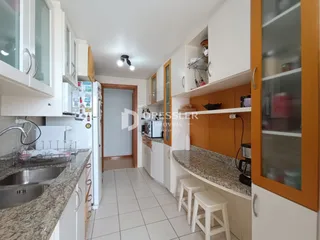 Interior de uma cozinha com armários brancos e piso de cerâmica.