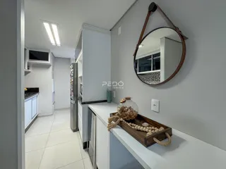 Vista interna de uma cozinha moderna com armários brancos e piso claro.
