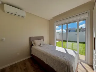 Quarto com cama e porta de vidro que dá acesso a um quintal gramado.
