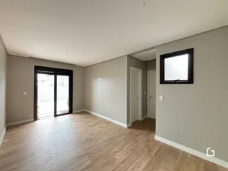Ambiente interno com piso de madeira clara e portas de vidro.