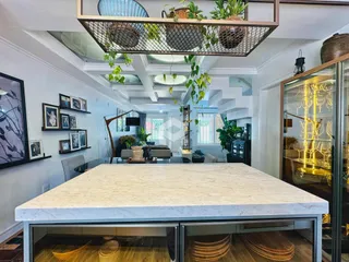 Ambiente de sala de estar com piso de madeira e teto alto.