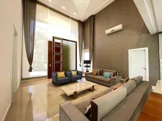 Sala de estar ampla com sofá e grandes janelas que proporcionam muita luz natural.