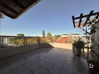 Área externa com piso de cerâmica e grade de madeira.