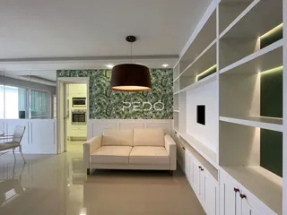Sala de estar moderna com sofá e estantes brancas em um imóvel no Brasil.