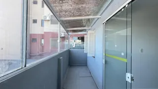 Corredor interno de um imóvel com divisórias de vidro e paredes cinzas.