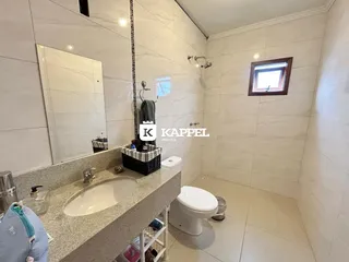 Banheiro com revestimento de azulejos brancos e pia de granito.