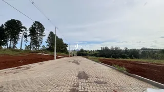 Uma estrada pavimentada com blocos de concreto se estende por uma área de terra.