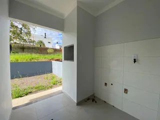 Vista de um pátio gramado a partir de um corredor interno com piso claro.