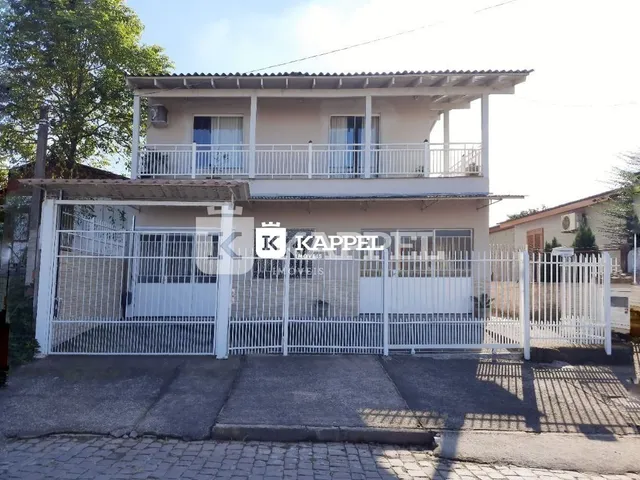 Fachada de uma casa em Lajeado, Brasil, com grade de segurança branca e varanda no segundo andar.