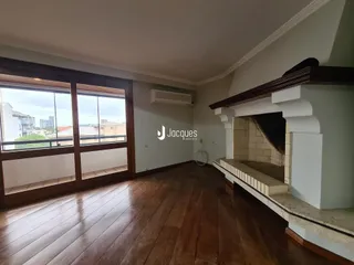 Interior de uma sala de estar com piso de madeira e grandes janelas.