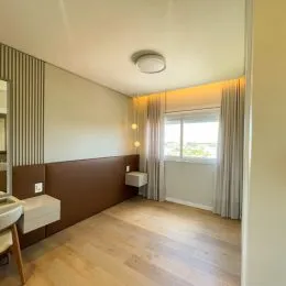 A sala apresenta piso de madeira e cortinas claras.