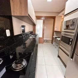 Foto de uma cozinha com bancadas escuras e eletrodomésticos de aço inoxidável.