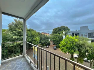 Vista de uma varanda com grade de ferro sobre uma área externa.