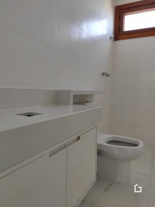 Foto da área do banheiro com bancada branca e vaso sanitário.