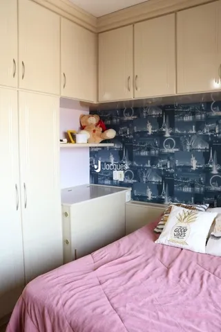 Quarto com cabeceira e armários em tom claro.