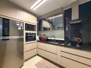 Interior de uma cozinha moderna com armários e eletrodomésticos em tons neutros.