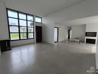 Sala de estar ampla com piso de cerâmica e grandes janelas.