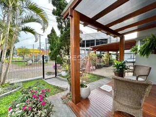 Vista da fachada de uma residência com deck de madeira e jardim em Lajeado.