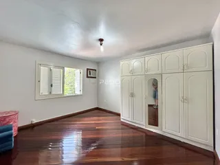 Sala de estar com piso de madeira escura e armários brancos.