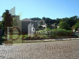 Vista externa de uma propriedade com paisagismo e calçamento de paralelepípedos.