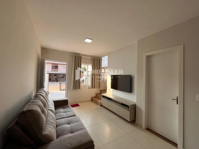 Sala de estar com sofá e piso de cerâmica clara.