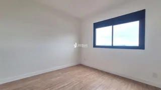 Uma sala de estar vazia com piso de madeira clara e uma grande janela.