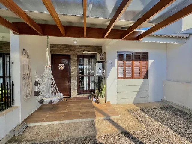Vista da área externa de uma residência com piso de cerâmica e estrutura de madeira.