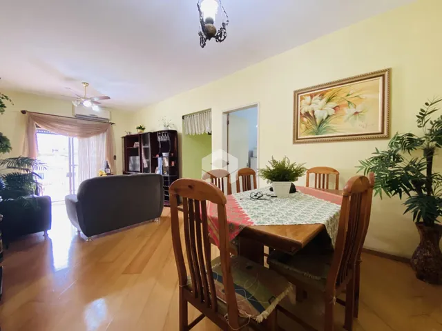 Sala de estar com piso de madeira e mesa de jantar em ambiente claro.