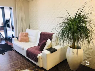 Sala de estar com sofá branco e piso de madeira clara.