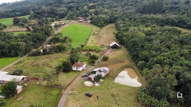 Vista aérea de uma propriedade rural com áreas de mata e campos.