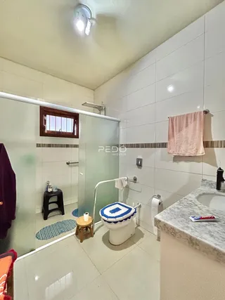 Foto interna de um banheiro com revestimento cerâmico branco.