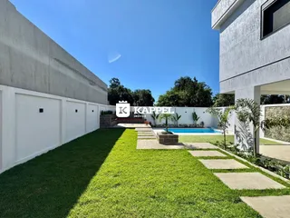 Fachada de uma casa moderna com gramado e piscina em um dia ensolarado.