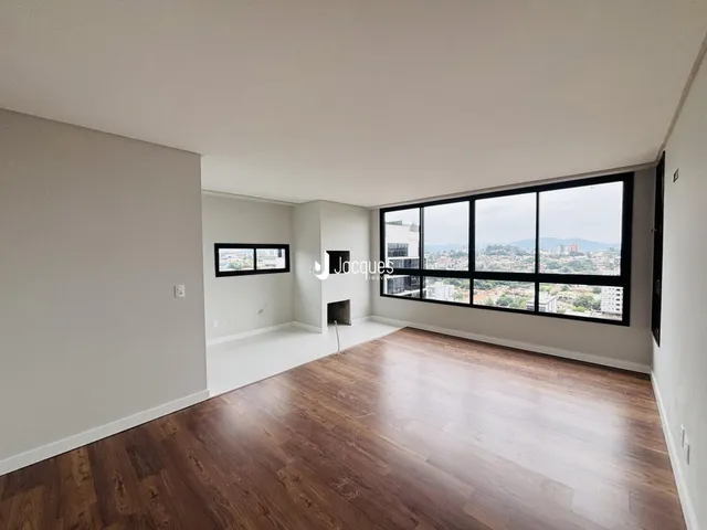 Ambiente interno de uma sala com piso de madeira e grande janela.