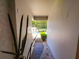 Foto de um corredor que leva a uma área externa com vegetação e piscina.