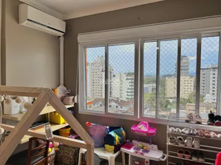 Vista interna de um cômodo com grande janela de vista para a cidade.