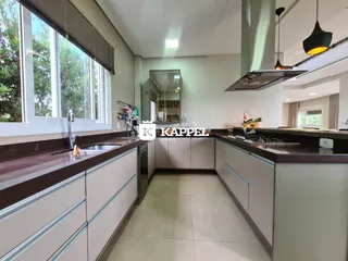 Cozinha moderna com bancadas escuras e grandes janelas.