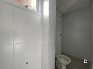 Vista interna de um banheiro com paredes brancas e vaso sanitário.