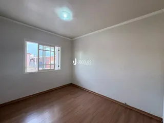 Ambiente interno de uma sala com piso de madeira clara e parede branca.