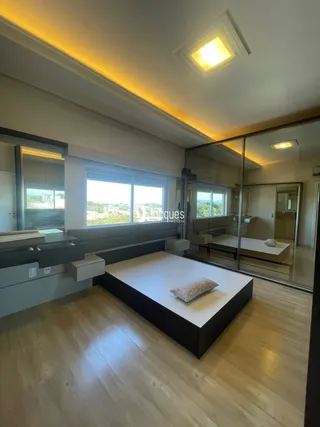 Sala de estar com piso de madeira clara e grande janela.